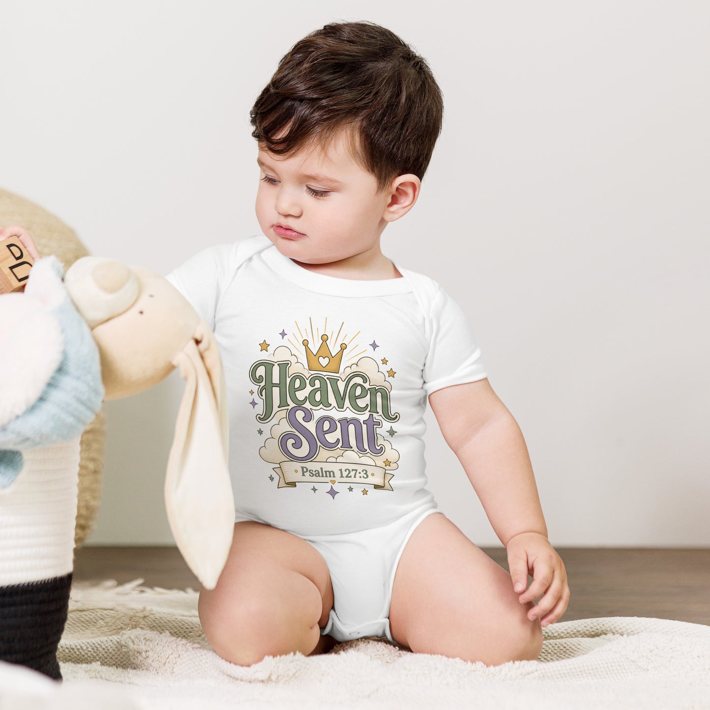 Christian baby onesie design reading Heaven Sent with Psalm 127:3, featuring a crown, clouds, stars, and soft green, lavender, cream, and gold colors.
