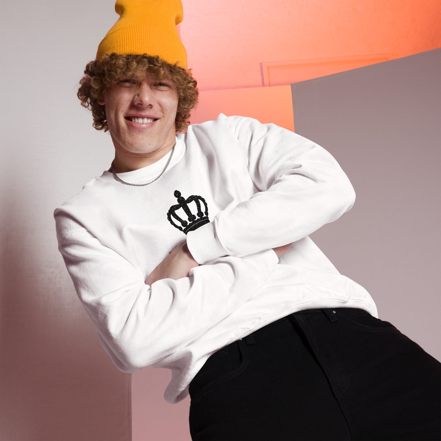 Person wearing a white sweatshirt with a black crown design and an orange beanie against a gradient background