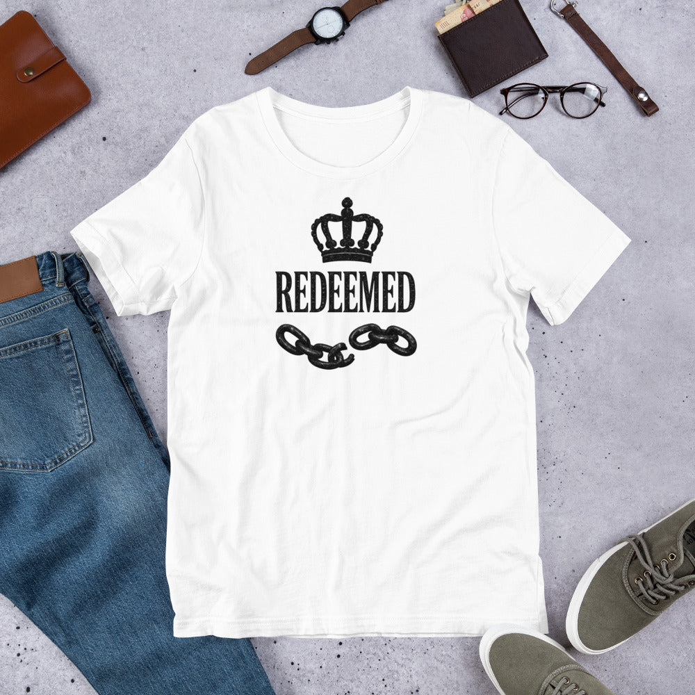Christian t-shirt featuring a black crown, broken chains, and Redeemed typography in luxury faith streetwear style.